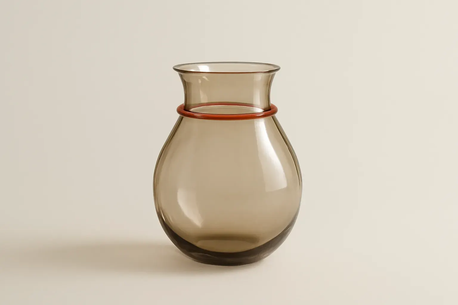 A hand-blown glass vessel on a pale ground with a coral reflection.